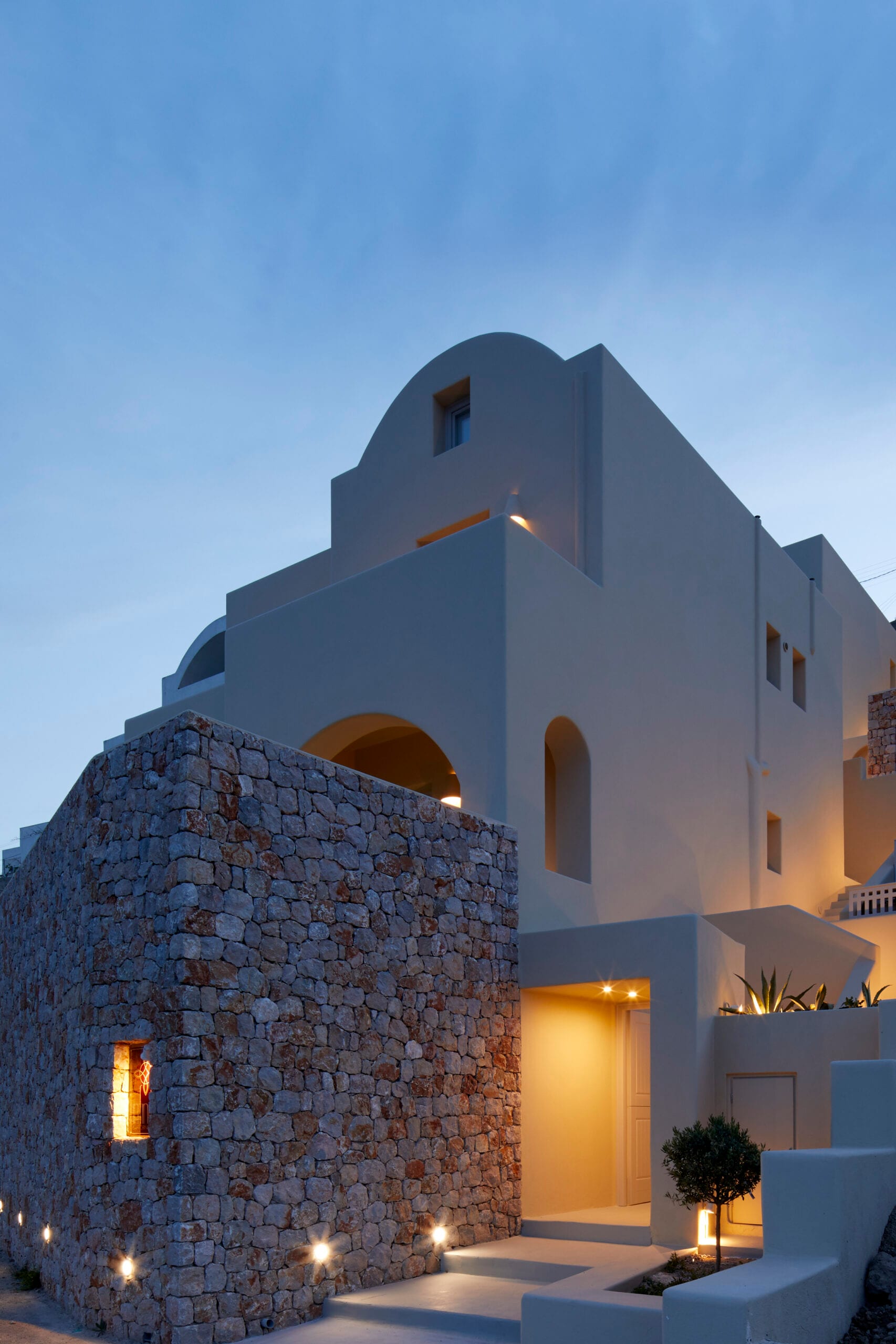 Star Infinity Suites at dusk — whitewashed Cycladic architecture and natural-stone walls in Pyrgos, Santorini